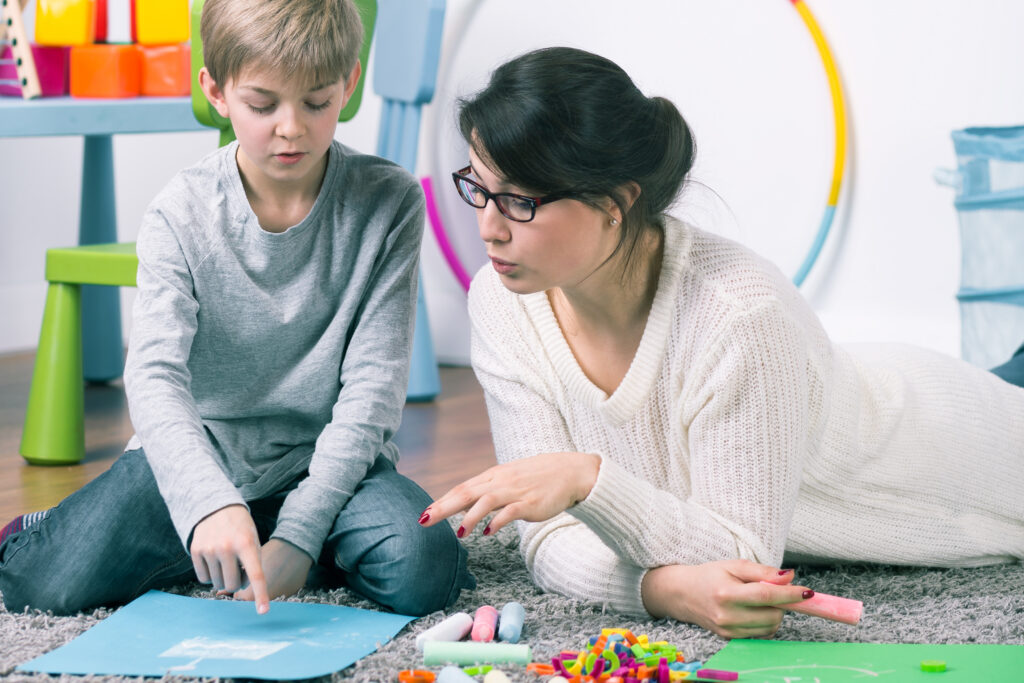 Boy and female therapist working with commitment on the carpet