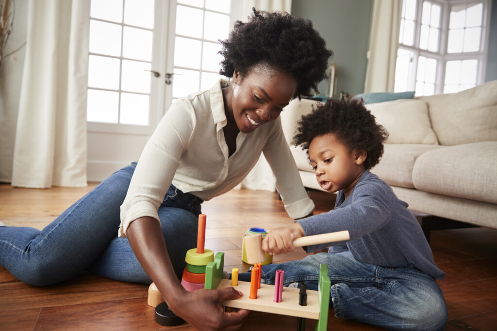 Mother And Young toddler with autism on the spectrum Playing With Wooden Toy At Home