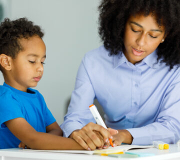 An RBT helping an individual with ASD write.