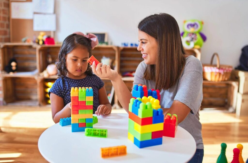 A caring ABA therapist at Kids Club ABA in New Jersey, guiding a child through a therapy session.